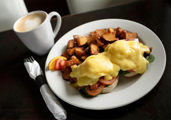 Eggs Benedict and hashbrowns served with a latte