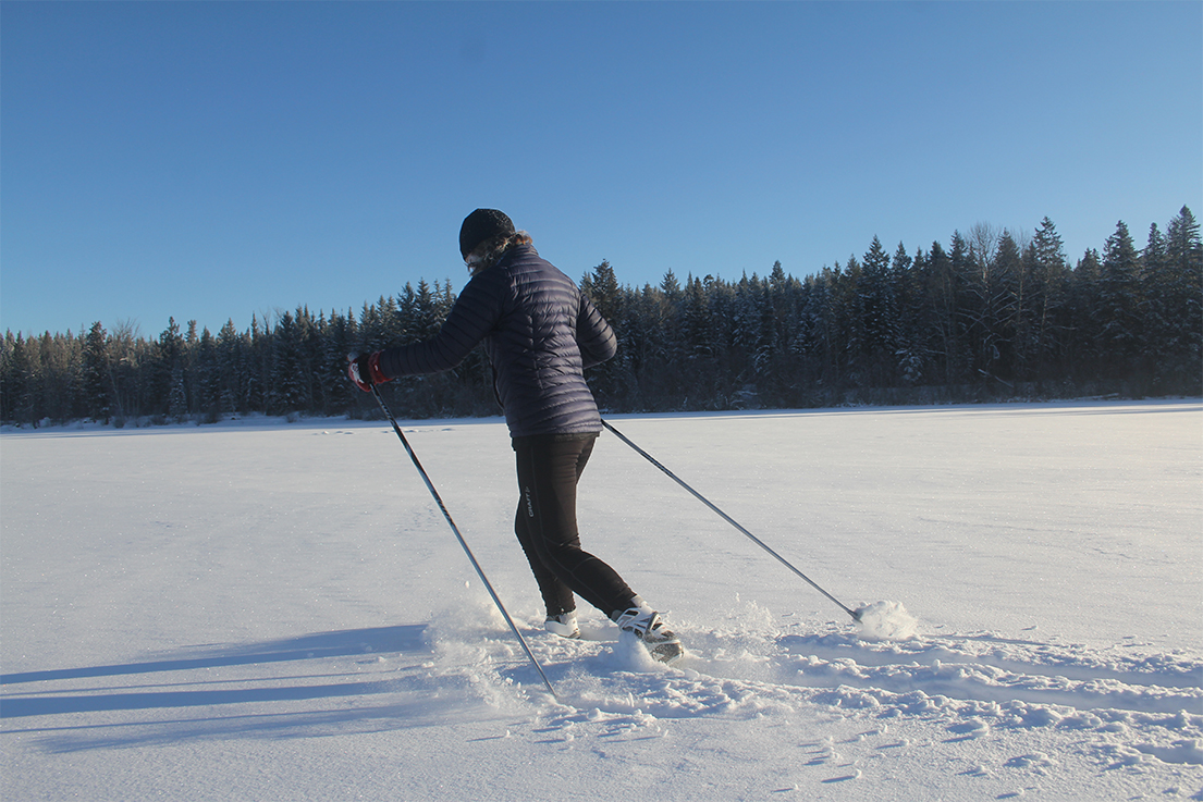 Woman cross-country skiing through fresh powder on Dragon Lake