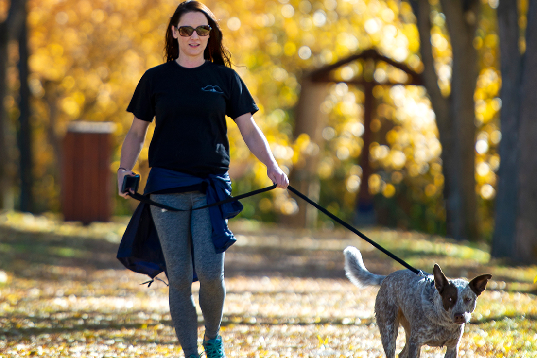 Woman walking her dog among fall colours on the Riverfront Trail