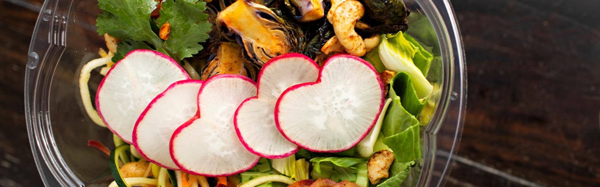 A bowl of salad locally grown produce with Radishes, Romaine lettuce, zucchini, cilantro, lentils 