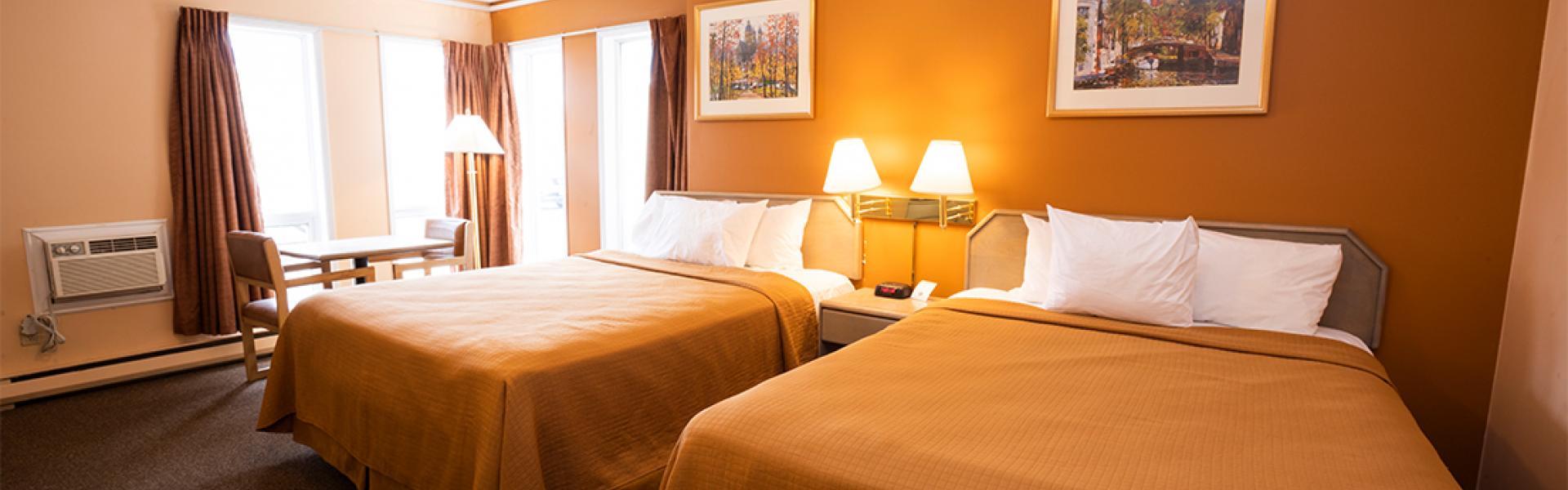 Clean and spacious bedroom with two queen size bed, seating area, and air – condition 