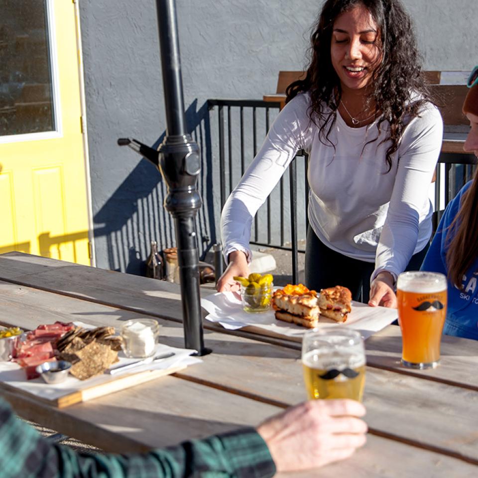 A couple being served food and craft beer on Barkerville Brewing's patio.