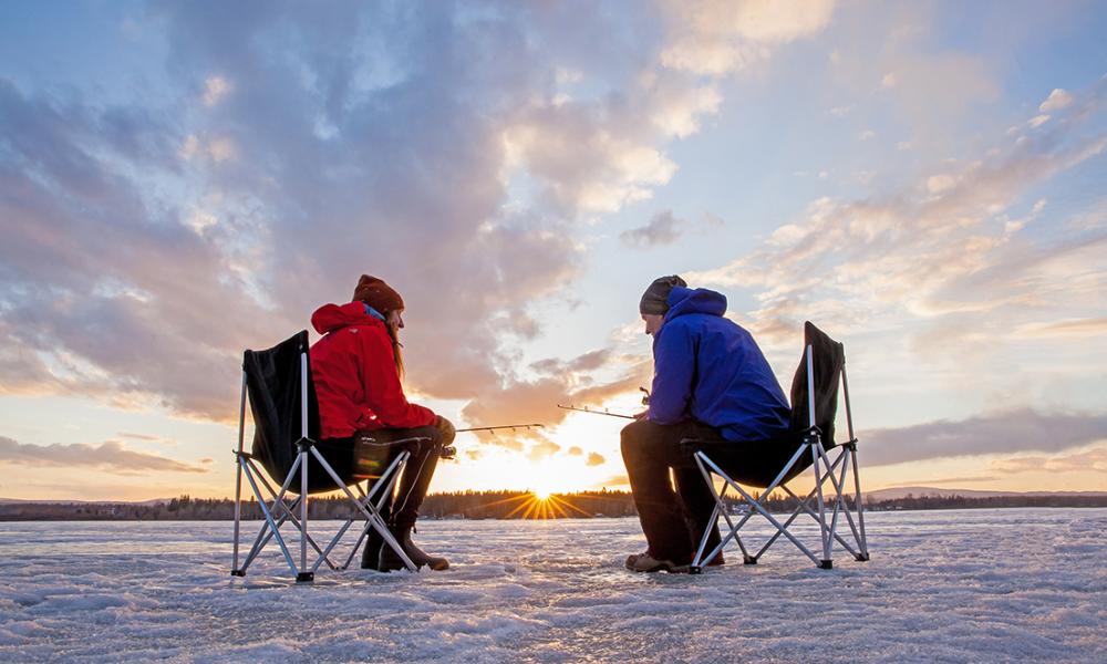 A couple ice-fishing on Dragon Lake during a beautiful sunset