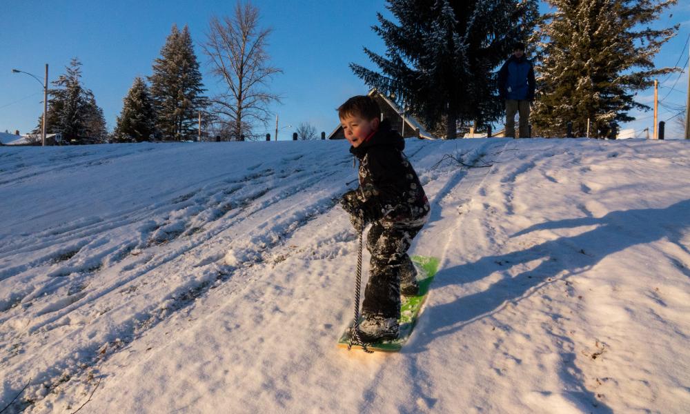 Young boy snowboarding down the hill at LeBourdais Park