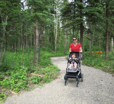 Mother pushing her young child in a stroller on an accessible trail