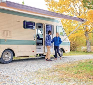 A couple outside of their RV on a fall day
