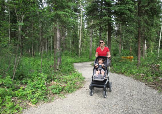 Mother pushing her young child in a stroller on an accessible trail