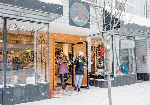 Two women walking out of Rocky Peak Adventure Gear with skis